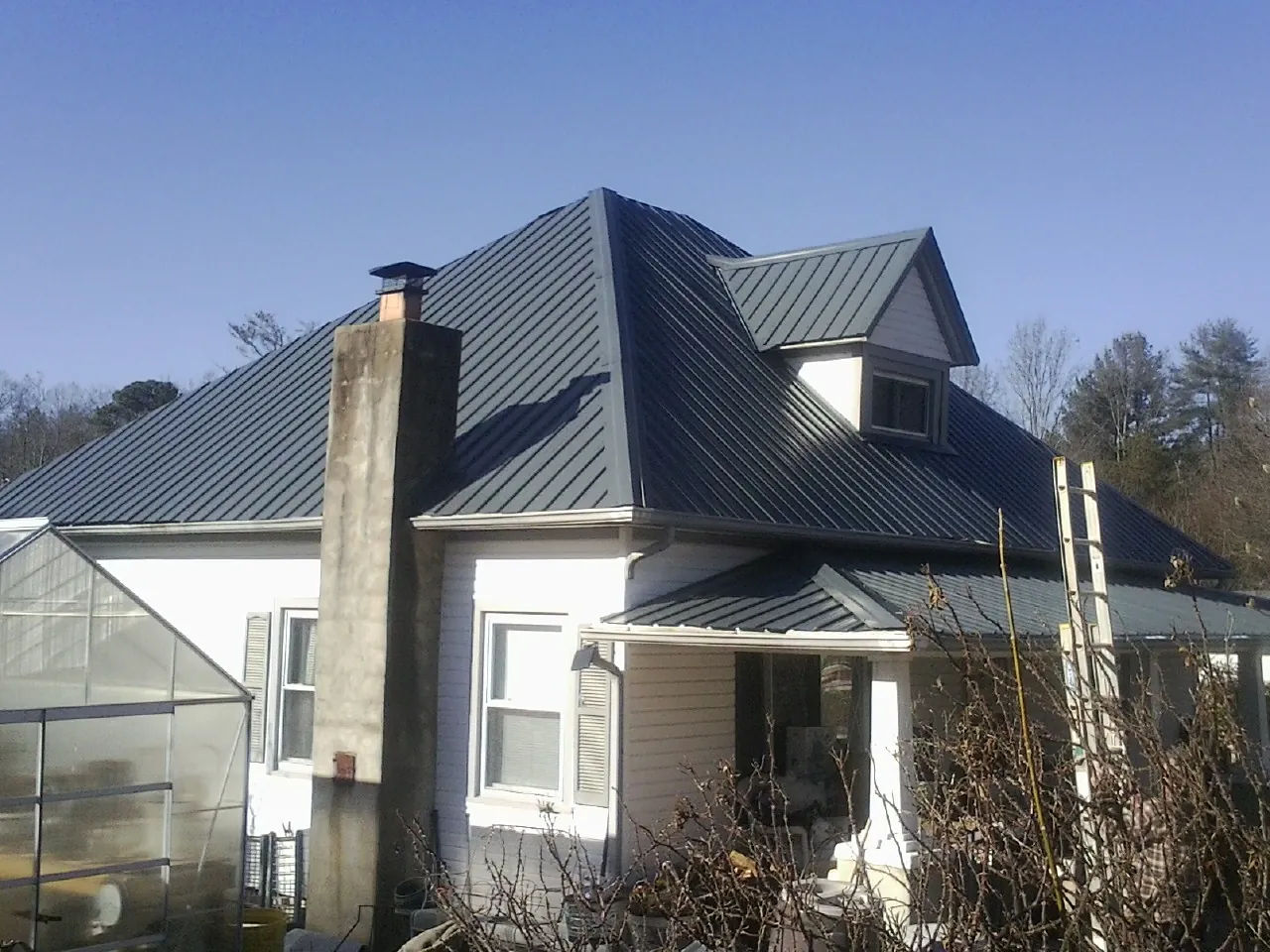 Dark blue standing seam metal roof on a white farmhouse with dormer — Slate & Tile Roof Repair by Roofing Brothers in Lompoc