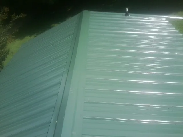 New green metal panels meeting at the ridge of a roof — Flat Roof Repair work by our crew in Lompoc