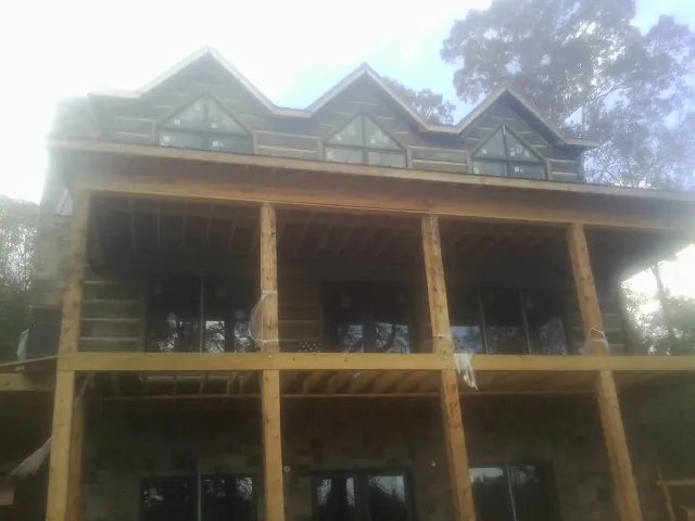 Dormers and porch framing on a large log home under construction — Roof Coating work by our crew in Lompoc
